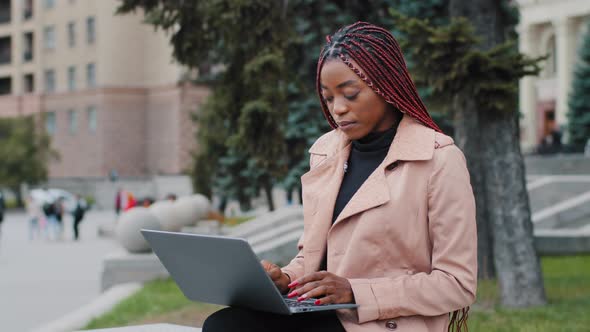 Focused Attractive Young African American Lady Businesswoman Working on Laptop Sitting Outdoors