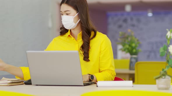 Asian business woman wearing face mask looking laptop working