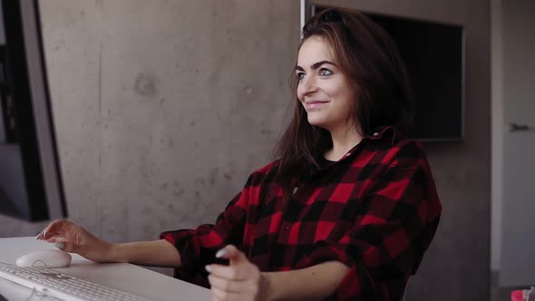 Young Attractive Girl is Being Emotional About Something While Typing Sitting in a Cozy Living Room