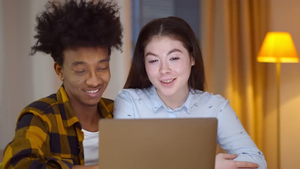Young Multiethnic Couple Shopping Online on Laptop at Home