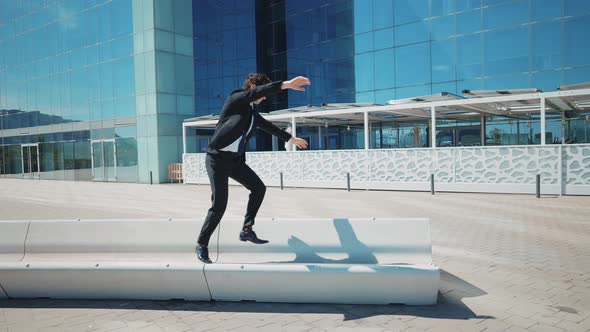 Flexible and cool businessman doing acrobatic tricks outdoor.