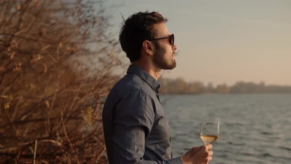 Man Drinking Wine On Sunrise. Man Holding Glass Of White Wine.Winemaker Sommelier Smelling At Sunset