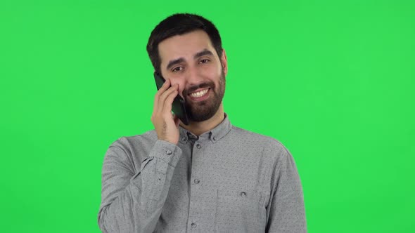 Portrait of Brunette Guy Is Talking for Mobile Phone and Rejoice. Green Screen