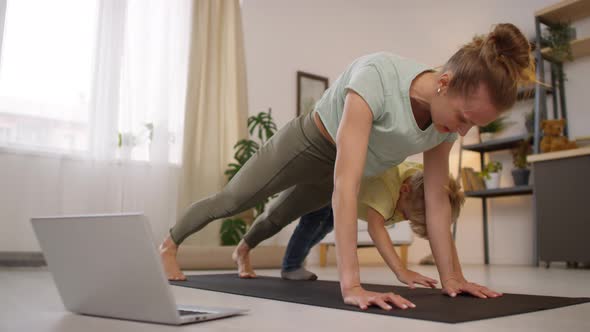 Female Yogi and her Child Doing Poses during Online Class
