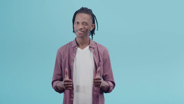 Black Man with Dreadlocks in a Shirt and Tshirt Shows Thumbs Up and Smiling Looking Into the Camera