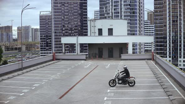 Man Starts a Motorbike and Drives on Top of the Multilevel Parking