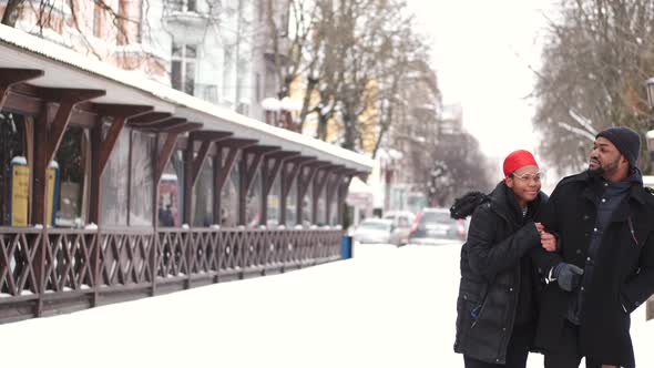 African American Couple in Warm Clothes Walking in the Winter City Together