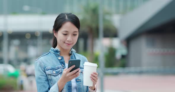 Woman use of mobile phone and holding coffee cup