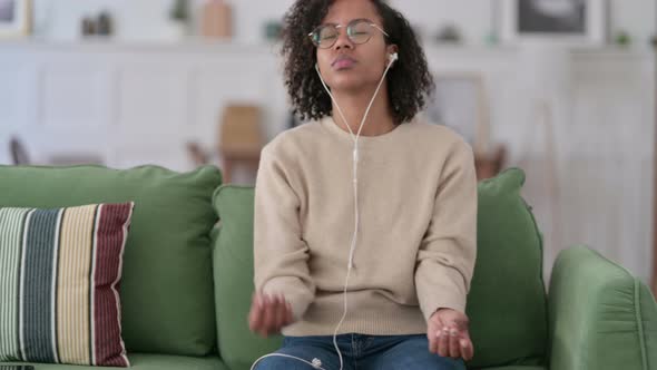 Young African Woman Meditating on Tablet on Sofa