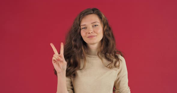 Female Studio Portrait Caucasian Millennial Girl Looking at Camera Posing on Red Background in