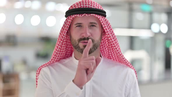 Serious Arab Businessman Putting Finger on Lips