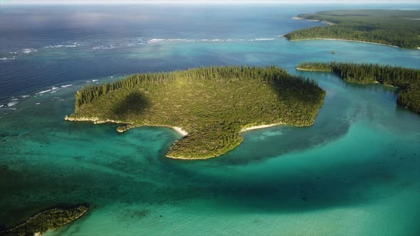 Aerial pan across small island near Oro Bay, Isle of Pines, highlighted with sunlight