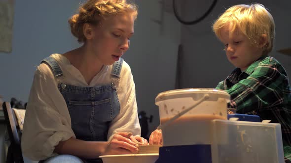 Woman and Boy Make Pot on Pottery Wheel in Workshop