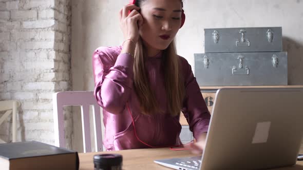 young woman sitting office interior using laptop computer and listening music