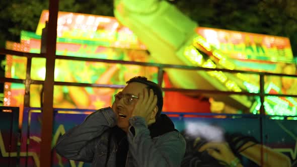Scared Yelling Man at Amusement Park with Crazy Spinning Attraction Behind