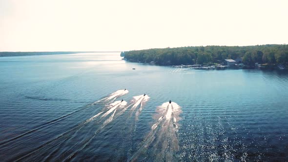 Gorgeous 4K aerial shot of jet skis speeding along a lake on a beautiful sunny day.