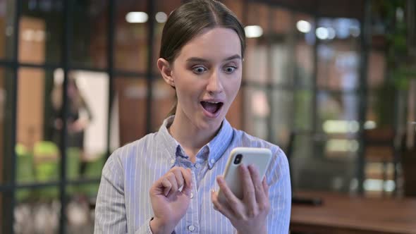 Young Woman Celebrating Success on Smartphone