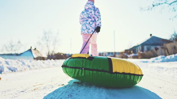 Funny Child Sliding on Snow Tubing on Slope Outdoors in Winter