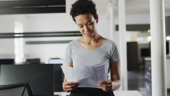 Focused biracial businesswoman checking documents in office