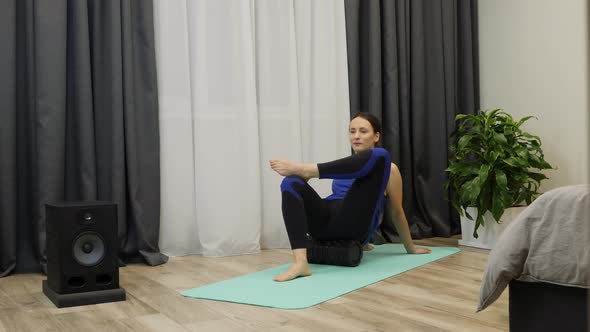 Fit well-trained woman does exercises with the fascia roll. Fitness and yoga concept