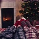 Over shoulder couple feet in christmas woolen socks near fireplace decorated tree tee cup in backg - VideoHive Item for Sale