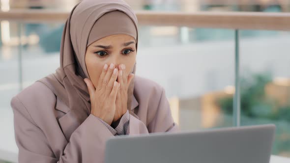 Sad Muslim Girl Student in Hijab Looking at Laptop Screen Reading Email Shocked By Bad News