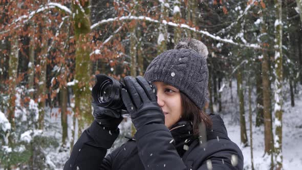 Beautiful woman do nature photography in forestry area during snowfall