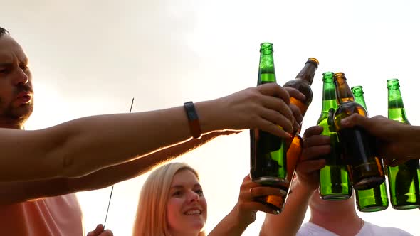 Happy friends dancing at sunset with a drink in their hands