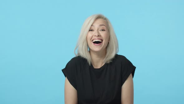 Slowmotion Gorgeous Adult Woman with Blond Short Hair Looking Camera Amused and Start Laughing Out