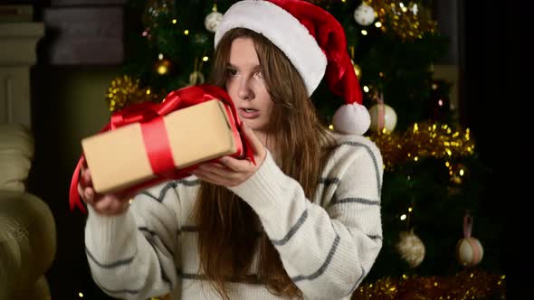 Happy girl unwrapping christmas present looking in box