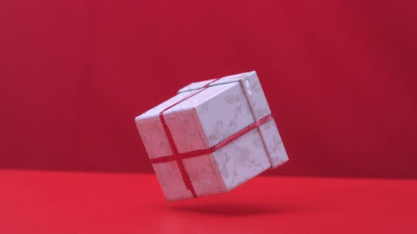 Christmas gift dropping and bouncing on red background