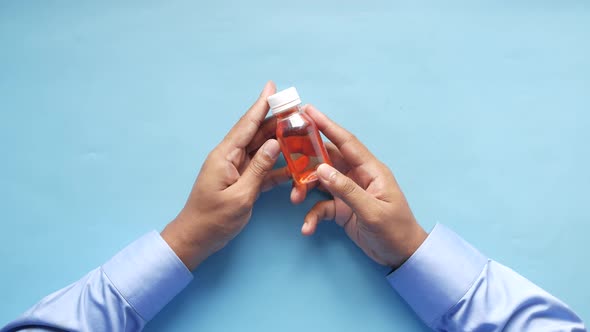 Hand Hold a Bottle with Liquid Medicine on Blue