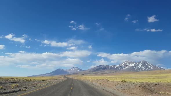 Atacama desert road and volcanoes on the horizon