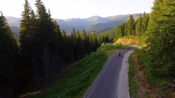 Motorcyclist driving his motorbike on the mountain road in the country side. Aerial view.