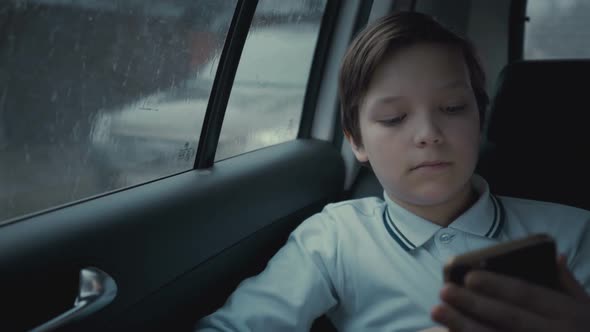 Unhappy  Boy Riding In Car Through City During Rainy Day