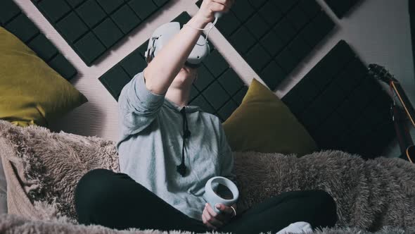 Young Woman in Virtual Reality Helmet Sitting on Sofa and Move Hands at Home