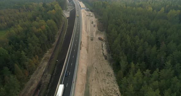 Aerial View of Highway Road Construction Site Between Green Forest