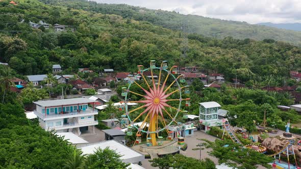 ferris wheel in amusement park in mountains of north bali on cloudy day, aerial