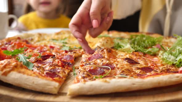 Closeup of Hands Taking Pizza From a Wooden Plate in a Cafe