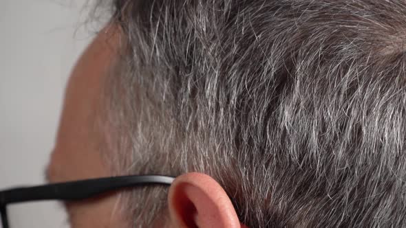 A Man Touches His Hands to the Gray Hair on His Head