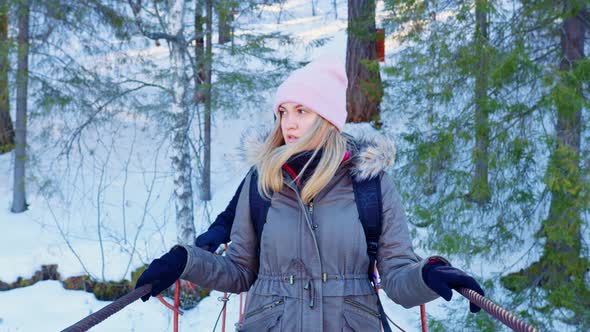 A Woman and a Man Walking on a Suspension Bridge in a Snowy Nature Park