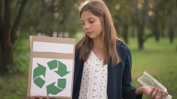 Cute Teenage Girl Looking at Box with Recycle Sign and Plastic Bottle Smiling Looking at Camera