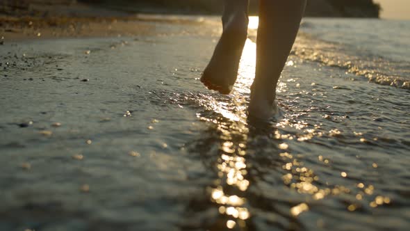 Walking feet on the coast with a beautiful sunset