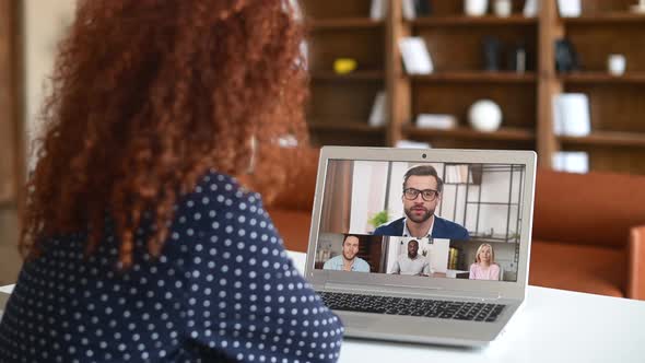 Back View Curly Woman Talking with Diverse Motivated Workteam on the Laptop Screen