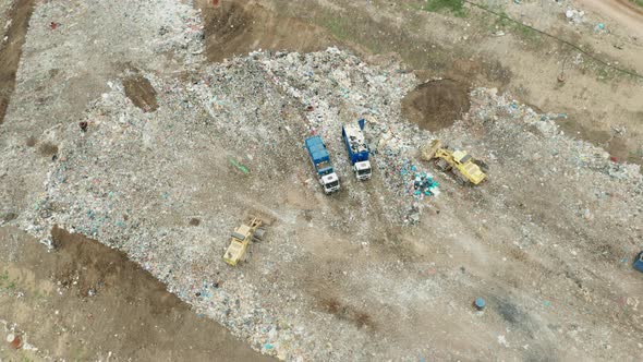 Top View on Garbage Trucks Unload Garbage to a Landfill
