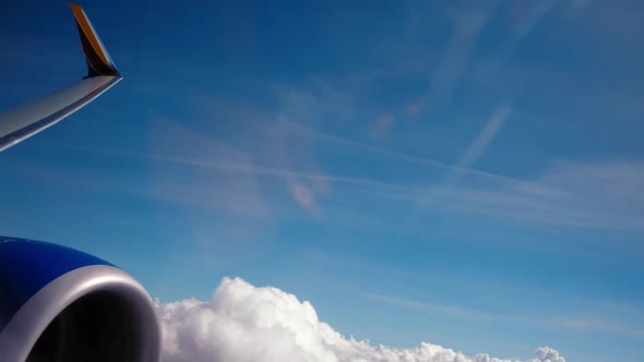 View from  the front of the wing as an airplane flies low over cluds and turns.