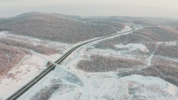 Drone Approach To the Road with Traffic Among the Hills in Winter