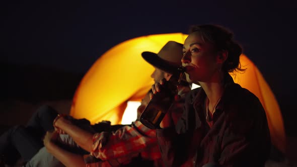 Woman Drinking Beer From Bottle at Campfire