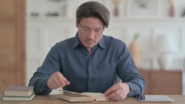 Man Reading Book while Sitting in Office