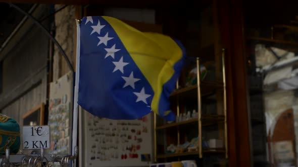 Small flag of Bosnia and Herzegovina fluttering in the wind outside a shop in Mostar